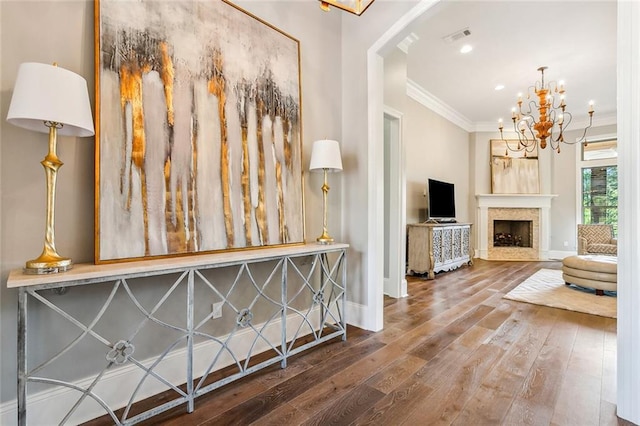 interior space featuring crown molding, visible vents, a chandelier, hardwood / wood-style floors, and baseboards