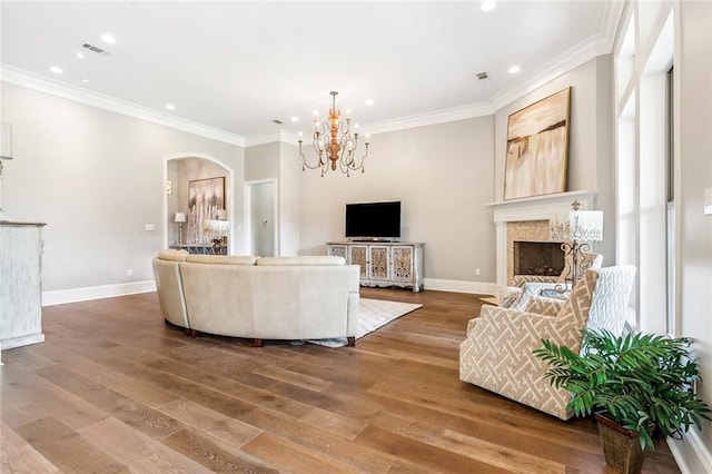 living room with arched walkways, wood finished floors, crown molding, and recessed lighting