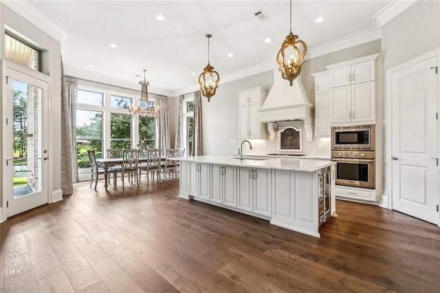kitchen with a notable chandelier, a sink, light countertops, appliances with stainless steel finishes, and crown molding
