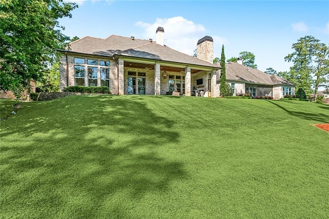 rear view of property featuring a chimney and a lawn