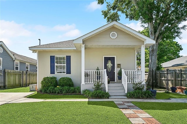 bungalow-style home featuring covered porch, stucco siding, roof with shingles, a front yard, and fence