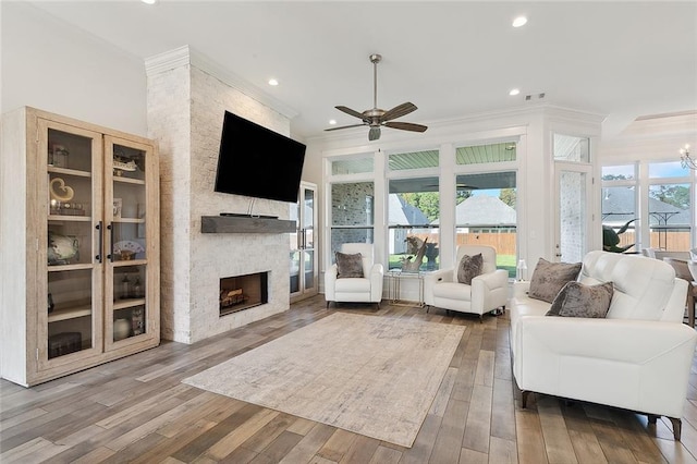 living area with recessed lighting, a ceiling fan, crown molding, hardwood / wood-style flooring, and a fireplace