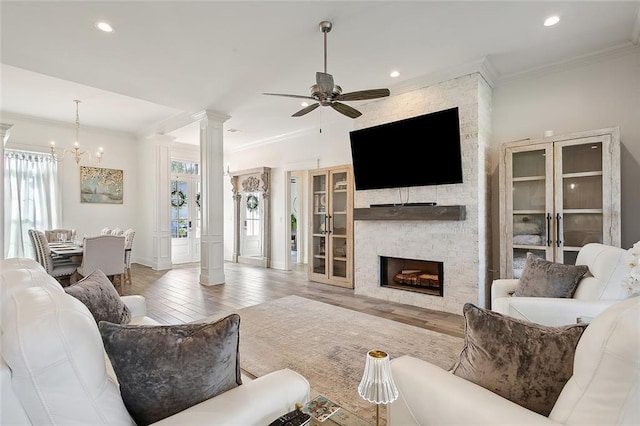 living room featuring ornate columns, ornamental molding, a fireplace, hardwood / wood-style flooring, and ceiling fan
