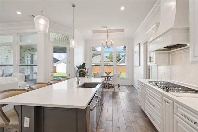kitchen featuring stainless steel appliances, light countertops, custom exhaust hood, and a sink