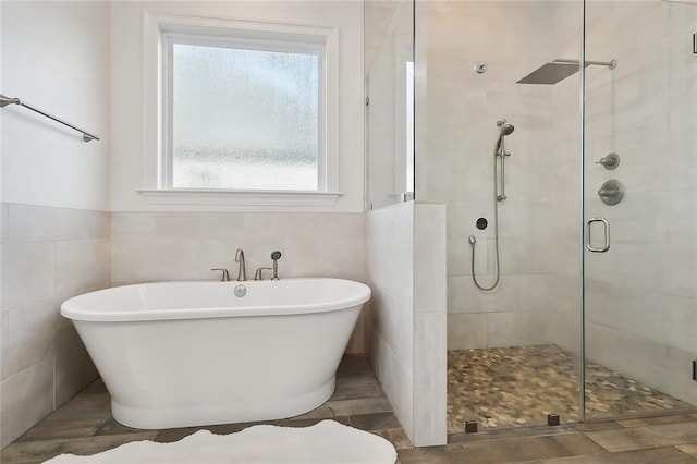 full bathroom featuring a freestanding bath, a shower stall, and tile walls