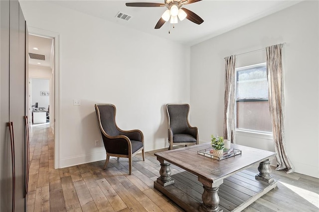 living area featuring visible vents, a ceiling fan, and light wood-style flooring
