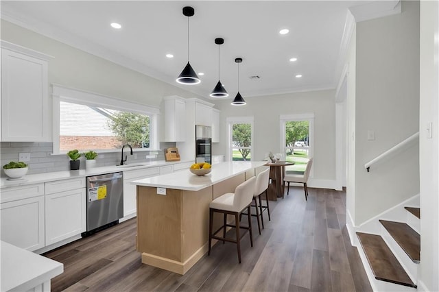 kitchen featuring a center island, crown molding, white cabinets, appliances with stainless steel finishes, and a sink