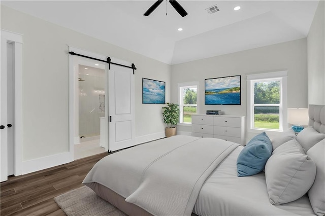 bedroom featuring recessed lighting, ensuite bath, a barn door, visible vents, and wood finished floors