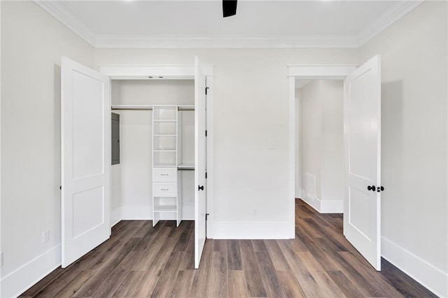 unfurnished bedroom featuring dark wood-type flooring, crown molding, a closet, and baseboards