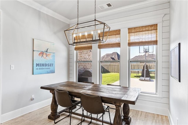 dining space featuring baseboards, an inviting chandelier, crown molding, light wood-style floors, and visible vents