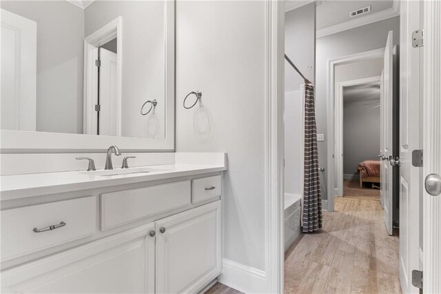 full bathroom featuring visible vents, shower / tub combo with curtain, crown molding, vanity, and wood finished floors