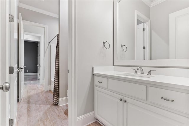 bathroom featuring wood finished floors, vanity, baseboards, and ornamental molding