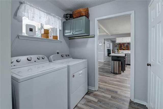 232 Chateau Dr, Slidell, LA 70460 - laundry area with cabinet space, washer and clothes dryer, light wood finished floors, and a textured ceiling