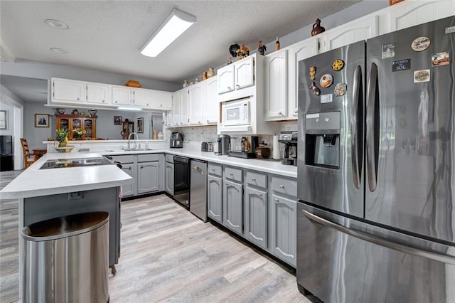 232 Chateau Dr, Slidell, LA 70460 - kitchen with appliances with stainless steel finishes, gray cabinets, light wood-style floors, light countertops, and a peninsula