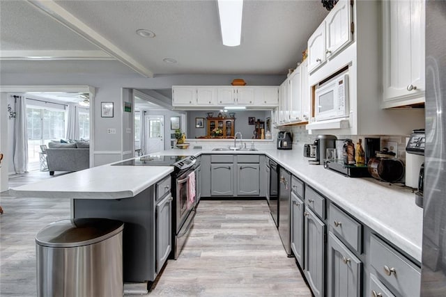 232 Chateau Dr, Slidell, LA 70460 - kitchen featuring appliances with stainless steel finishes, gray cabinets, light countertops, light wood-style floors, and decorative backsplash