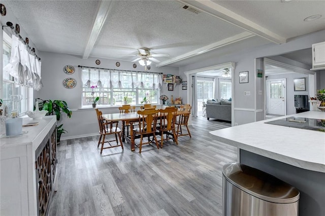 232 Chateau Dr, Slidell, LA 70460 - dining room featuring a textured ceiling, beamed ceiling, ceiling fan, and light wood-style flooring
