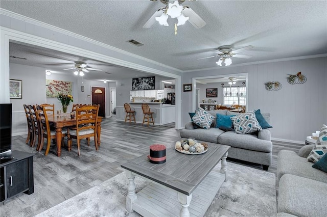232 Chateau Dr, Slidell, LA 70460 - living room featuring a ceiling fan, light wood-style flooring, a textured ceiling, and crown molding
