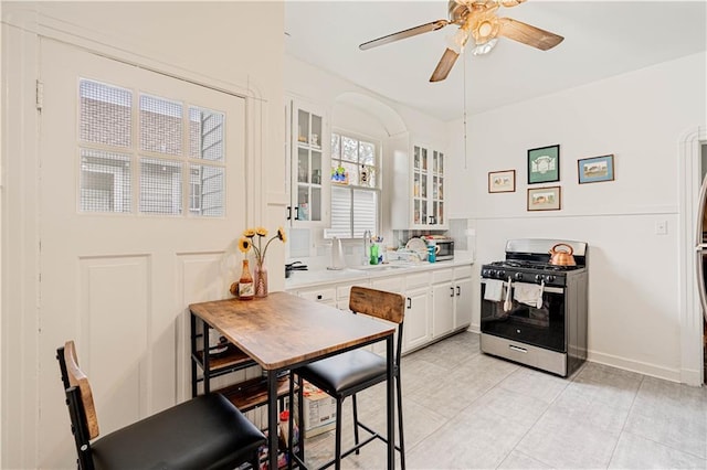 8632 Apple St, New Orleans, LA 70118 - kitchen with white cabinets, a sink, light countertops, a ceiling fan, and gas range