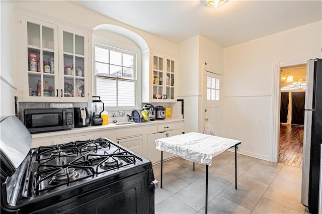 8632 Apple St, New Orleans, LA 70118 - kitchen featuring light countertops, white cabinets, light tile patterned floors, and black appliances