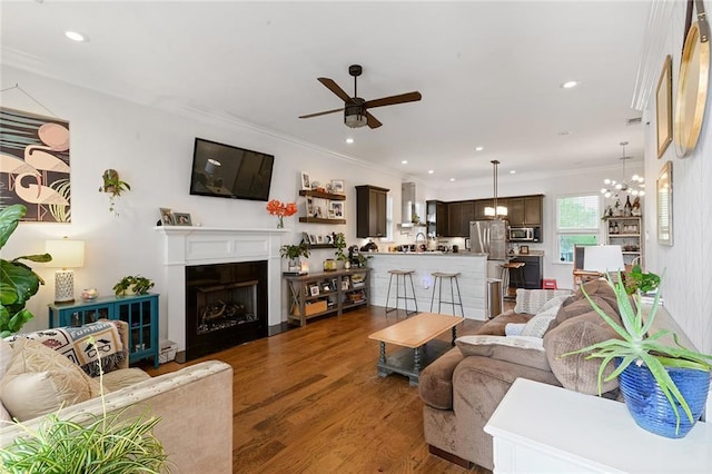 6038 Orleans Ave, New Orleans, LA 70124 - living room with ornamental molding, a fireplace with flush hearth, wood finished floors, and ceiling fan with notable chandelier