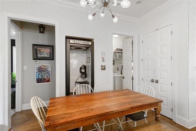 6038 Orleans Ave, New Orleans, LA 70124 - dining space featuring baseboards, a chandelier, crown molding, washer / dryer, and wood finished floors