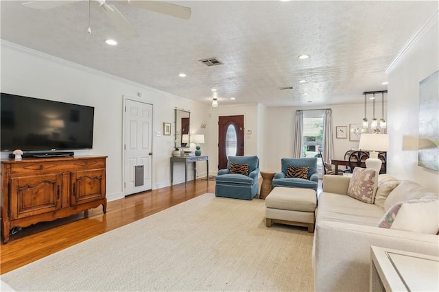 living room featuring crown molding, a ceiling fan, visible vents, recessed lighting, and wood finished floors