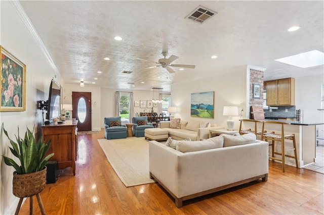 living room featuring crown molding, visible vents, recessed lighting, and light wood-style floors