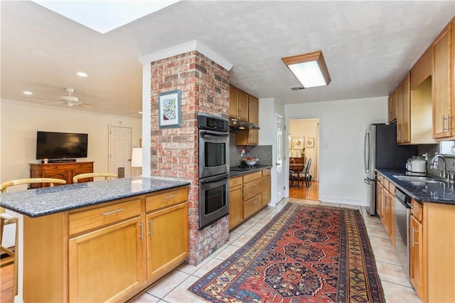 kitchen with a ceiling fan, backsplash, light tile patterned flooring, appliances with stainless steel finishes, and a sink