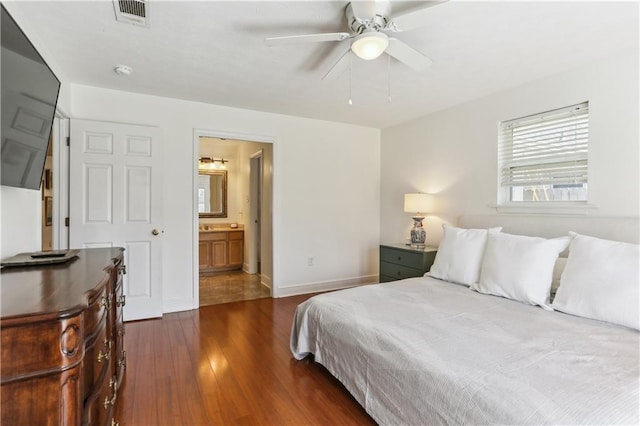bedroom with baseboards, ensuite bath, a ceiling fan, dark wood-type flooring, and visible vents