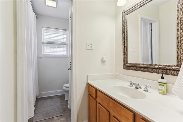 bathroom with toilet, vanity, baseboards, and tile patterned flooring