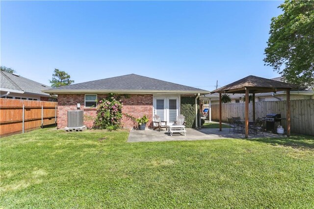 back of property with brick siding, a fenced backyard, central AC, and a patio