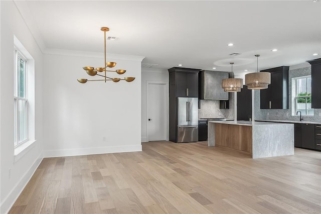 kitchen featuring tasteful backsplash, light countertops, a chandelier, high end refrigerator, and light wood-type flooring