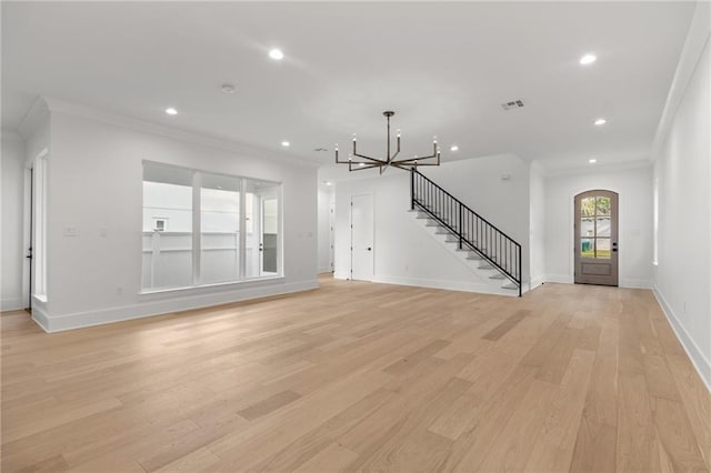 unfurnished living room with visible vents, ornamental molding, stairs, light wood-type flooring, and a notable chandelier