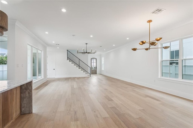 unfurnished living room with visible vents, crown molding, baseboards, a chandelier, and light wood-style flooring
