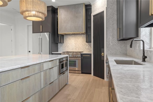 kitchen with backsplash, a sink, custom exhaust hood, light wood-style floors, and premium appliances