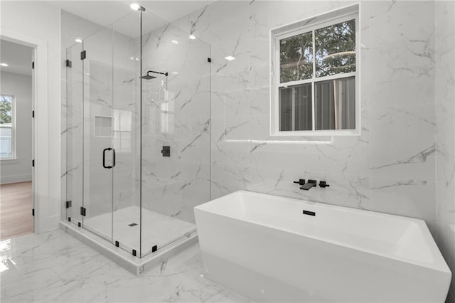 bathroom with a freestanding bath, a marble finish shower, and marble finish floor
