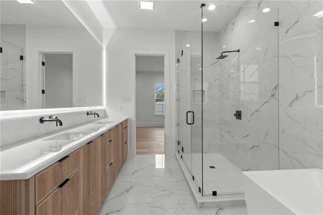 full bathroom with double vanity, a freestanding bath, a sink, marble finish floor, and a marble finish shower