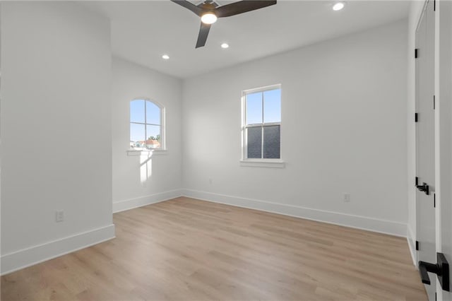 spare room featuring a ceiling fan, baseboards, plenty of natural light, and light wood-type flooring