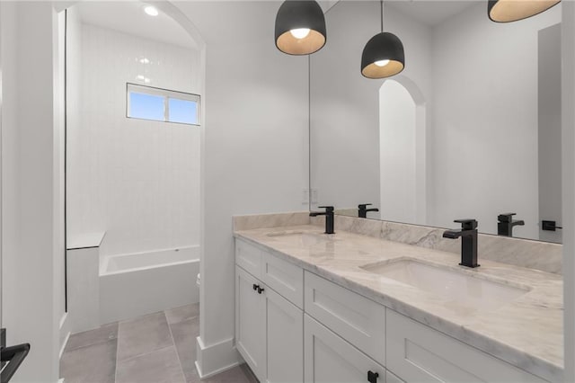 full bath featuring double vanity, tile patterned floors, washtub / shower combination, and a sink