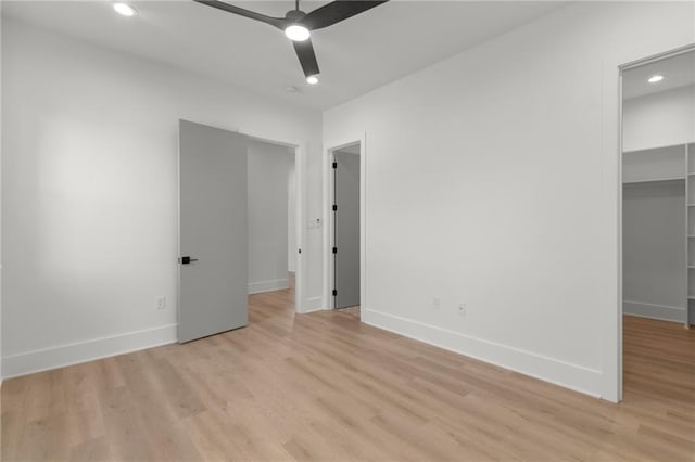 unfurnished bedroom featuring recessed lighting, a closet, a walk in closet, and light wood-type flooring