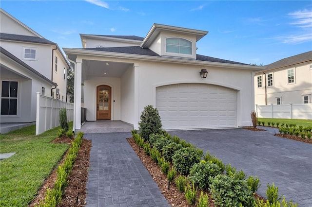 view of front of home with aphalt driveway, an attached garage, fence, and stucco siding
