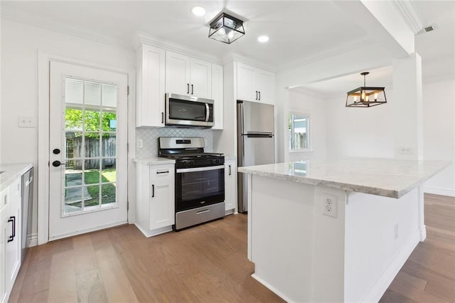 kitchen featuring crown molding, appliances with stainless steel finishes, and wood finished floors