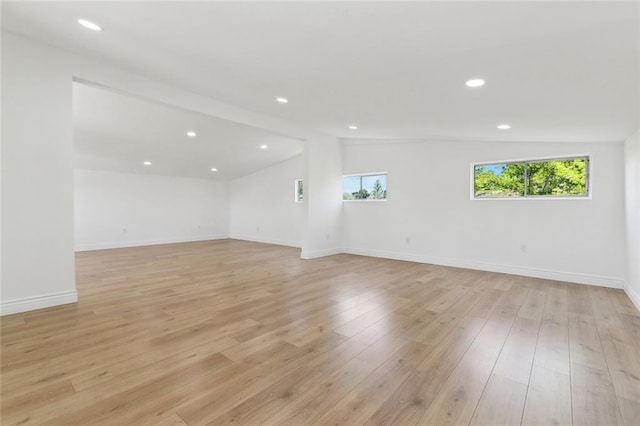 empty room featuring baseboards, recessed lighting, light wood-type flooring, and vaulted ceiling