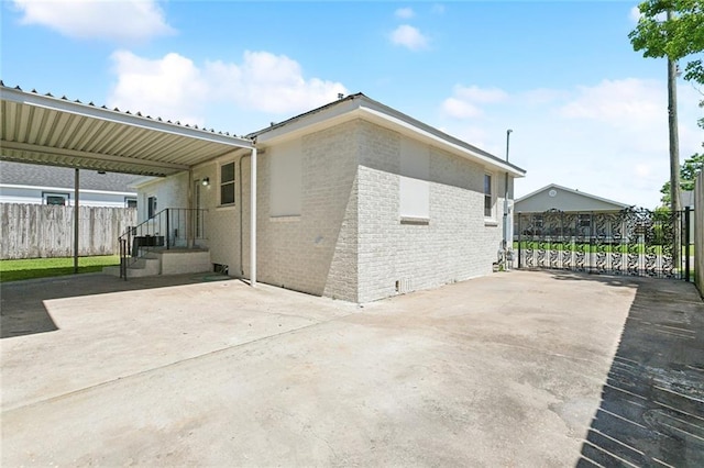 rear view of house with a patio area, fence, and brick siding