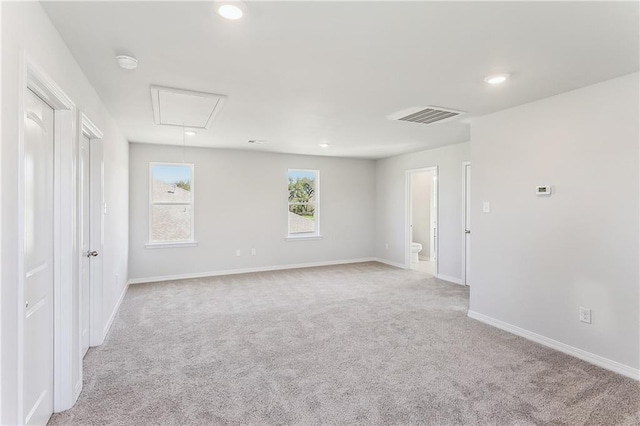 carpeted empty room featuring recessed lighting, visible vents, baseboards, and attic access
