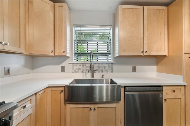kitchen with stainless steel dishwasher, light brown cabinetry, a sink, and light countertops