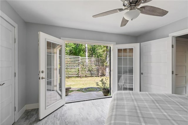 unfurnished bedroom featuring ceiling fan, baseboards, access to outside, and wood finished floors