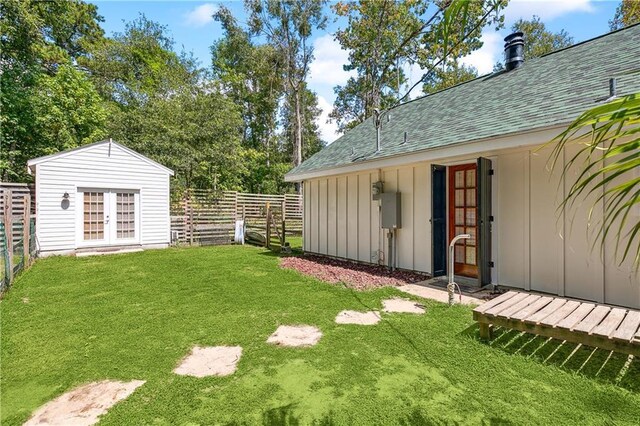 view of yard featuring french doors, fence, and an outdoor structure