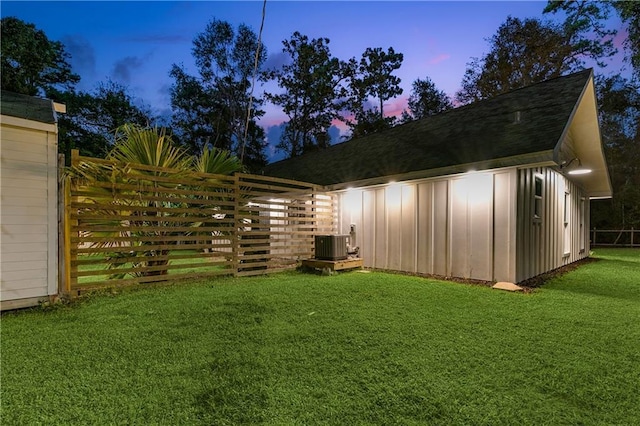 yard at dusk with central AC and fence