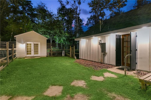 view of yard featuring an outbuilding, french doors, and a fenced backyard
